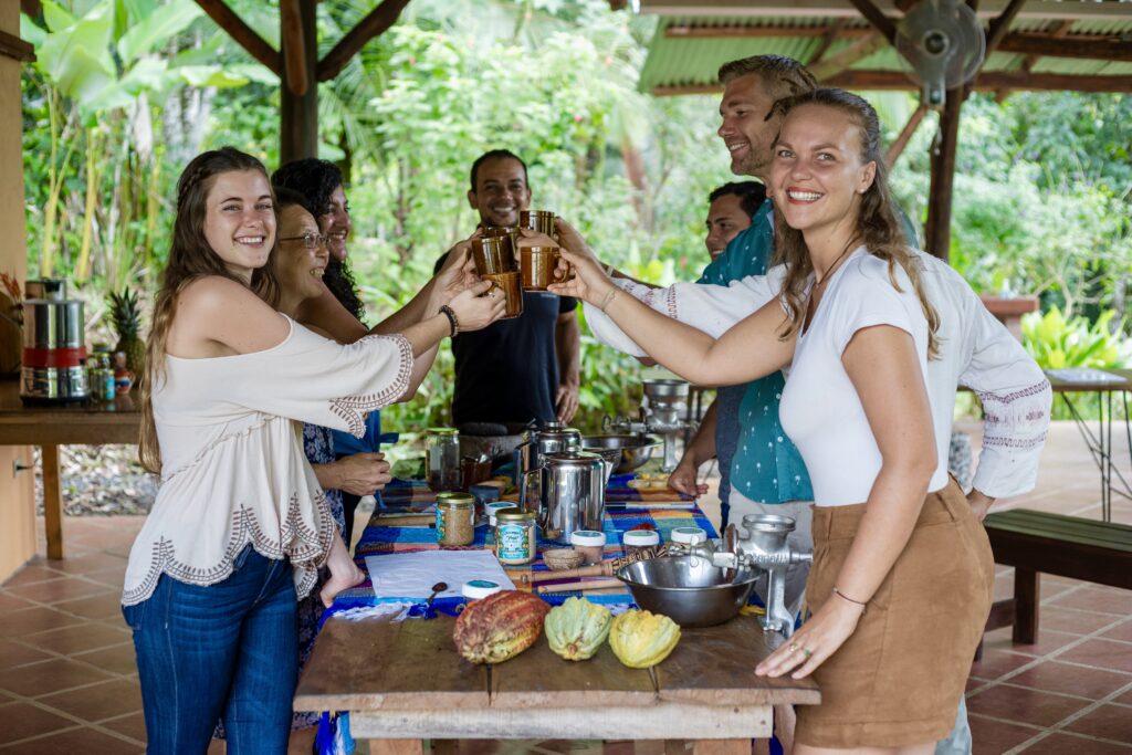 Happy tour guests smiling and toasting with artisanal farm hot chocolate