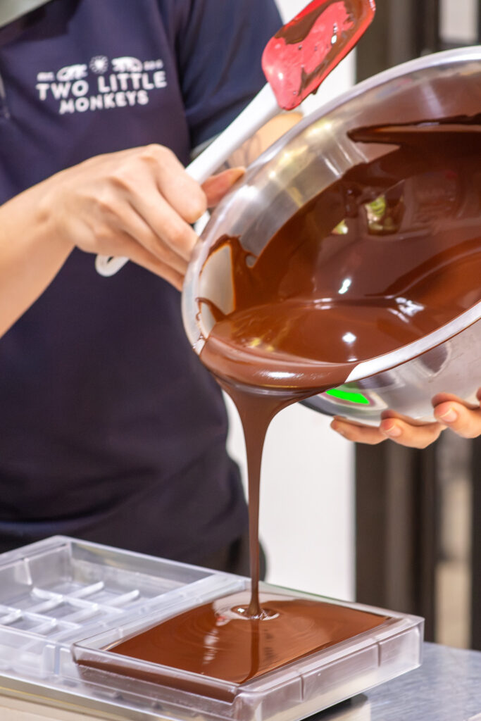 A chocolate maker filling a bar mold with melted chocolate