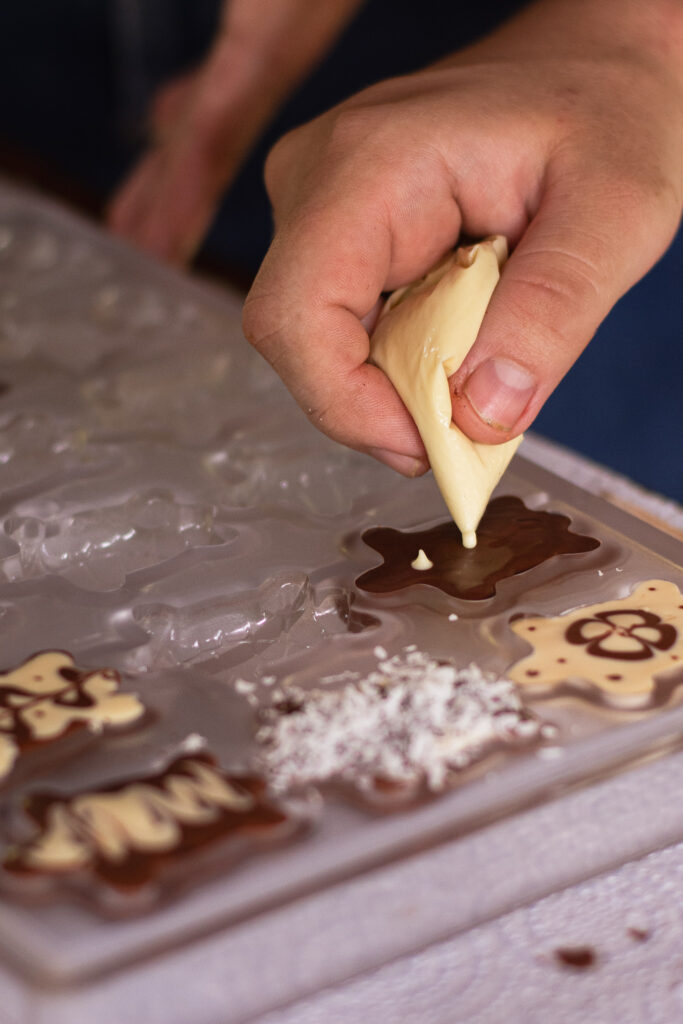 Decorating handmade chocolates with white chocolate and coconut