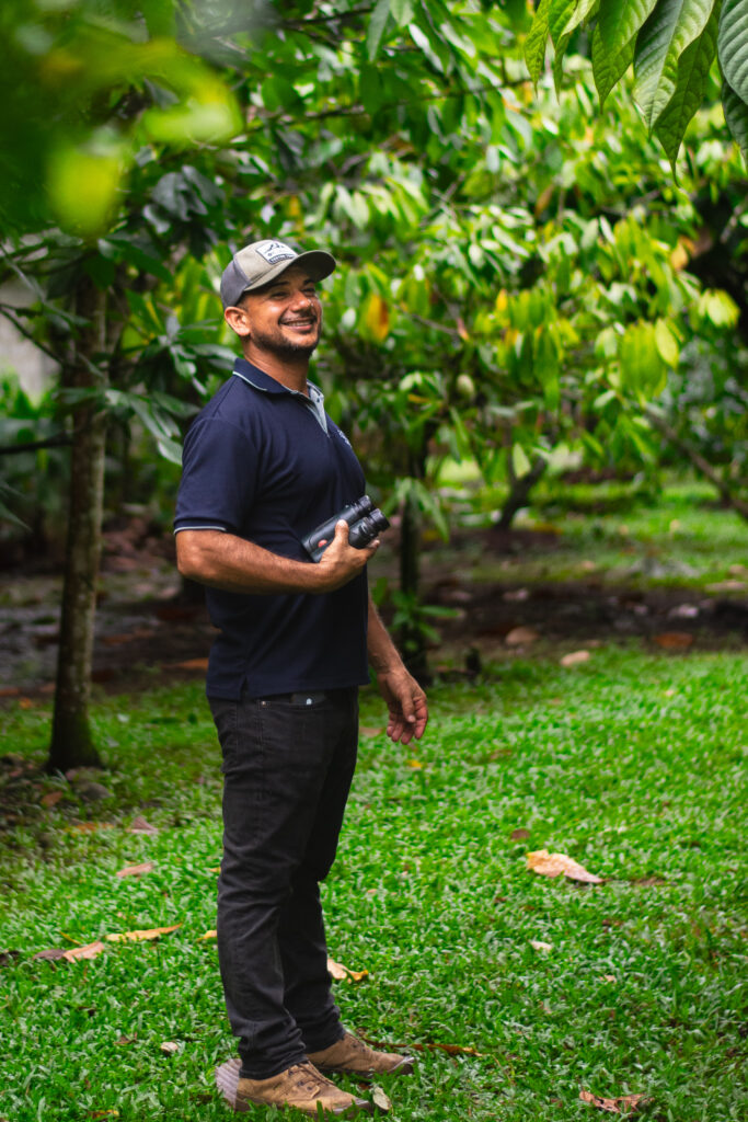 Ismael standing among the cacao trees on the farm