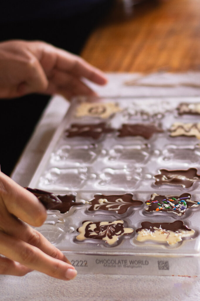 Hands filling a chocolate mold by hand