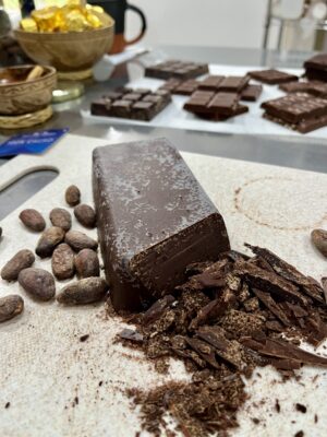 A block of 100% cacao, partly cut, with cacao beans and shavings