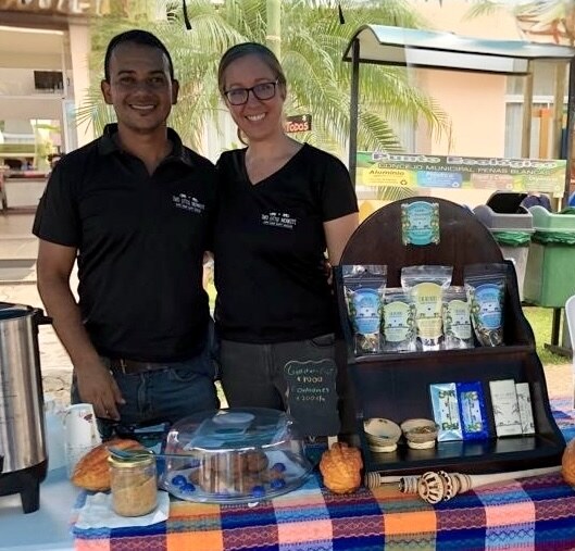 Ismael and Lindy standing behind their chocolate stand at a local market
