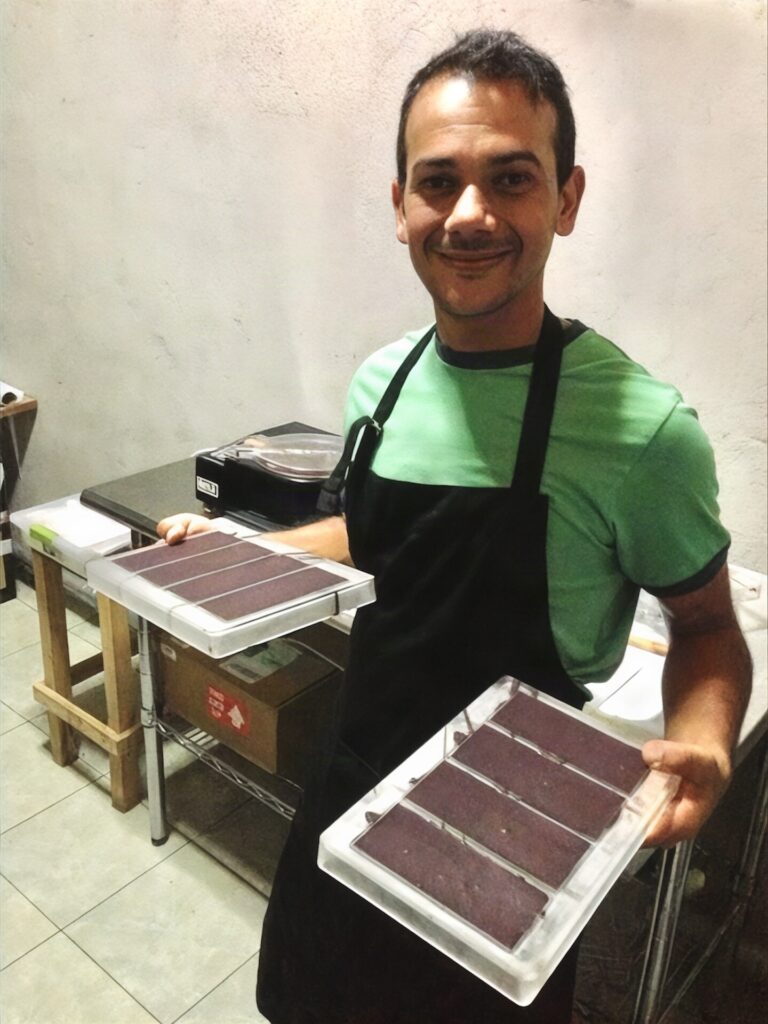 Ismael holding trays of freshly made chocolate bars in the early workshop